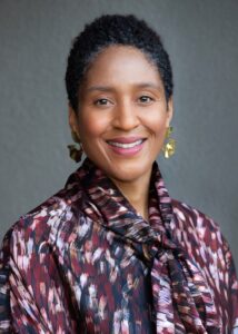 Headshot of a woman in a floral shirt and dangling earrings.