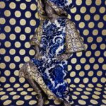 An art piece where a mannequin in covered in fabric against a bright wall also covered in fabric.