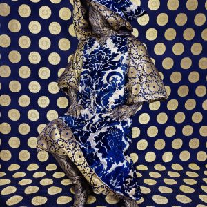 An art piece where a mannequin in covered in fabric against a bright wall also covered in fabric.