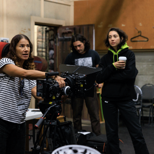 Professor instructs while holding camera as students listen