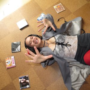 Person lying on a floor with headphones on, surrounded by CD cases.