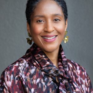 Headshot of a woman in a floral shirt and dangling earrings.
