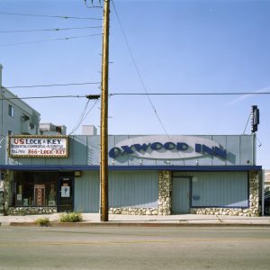 An exterior daytime shot of a one-story building called the Oxwood Inn. A telephone pole sits in front of the bar.